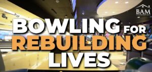 A bowling alley with the words BOWLING FOR REBUILDING LIVES in large, bold letters across the image. The BAM Companies logo is in the upper right corner.
